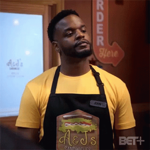 Man in Apron and Yellow Shirt With Sandwich Board