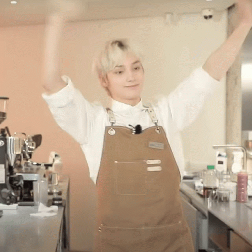Man in Apron with Arms Up in Kitchen