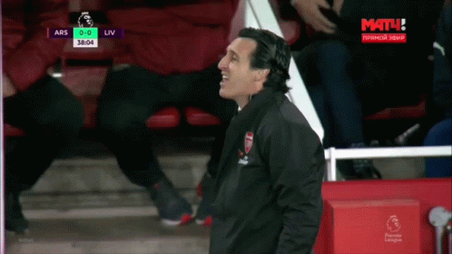Man in Arsenal Jacket in Front of Screen Saying Mat