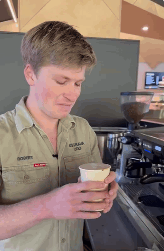 Man in Australia Zoo Shirt Holding Cup