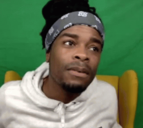 Man in Bandana and White Hoodie Sitting Before Green Screen