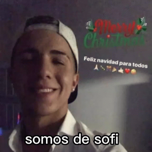 Man in Baseball Cap and White Shirt Smiling at Merry Christmas Sign