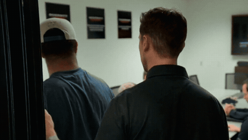 Man In Baseball Cap In Front Of Wall With Posters GIF