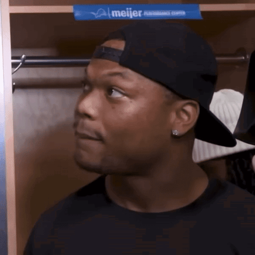 Man In Baseball Cap Standing In Locker With Meijer Advertisement GIF