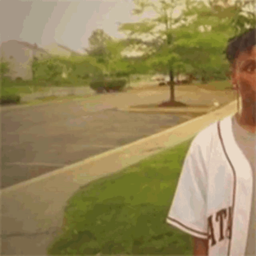 Man in Baseball Jersey on Parking Lot Sidewalk