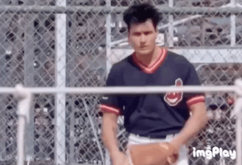 Man in Baseball Uniform Holding Baseball at Fence