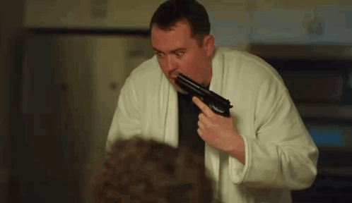 Man In Bathrobe Holding Gun GIF