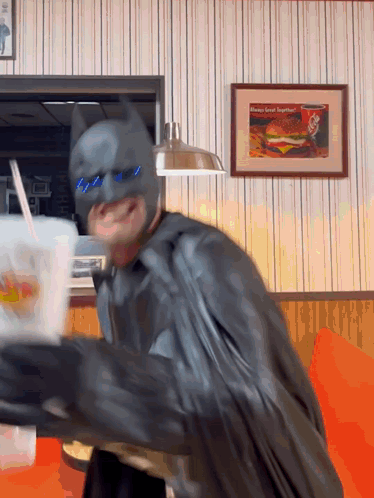 Man in Batman Costume Holding Drink