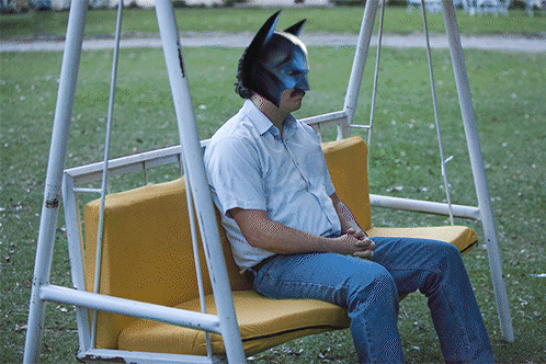 Man in Batman Mask Sitting on Yellow Swing