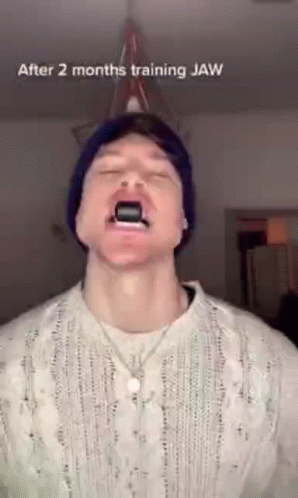 Man In Beanie And Sweater Using Jaw Trainer GIF