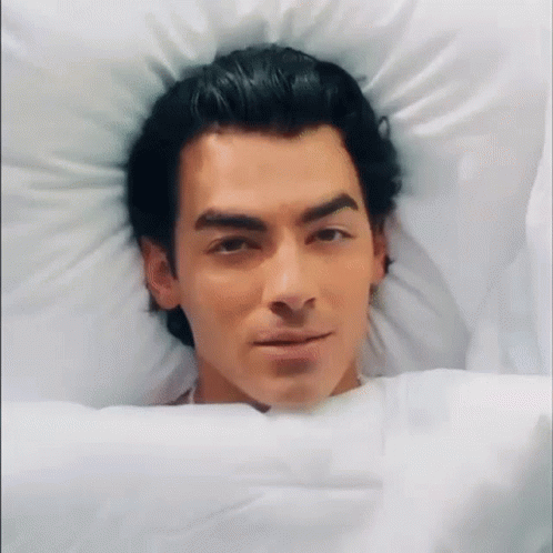 Man in Bed Head on Pillow Looking at Camera
