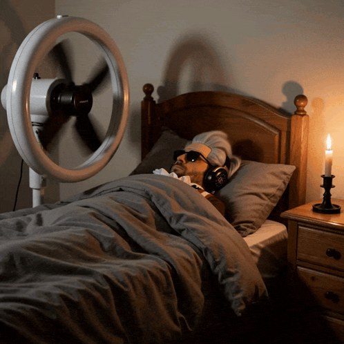 Man in Bed With Headphones Fan and Candle