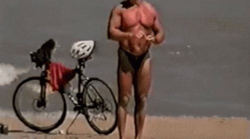 Man in Bikini Standing on Beach With Bike