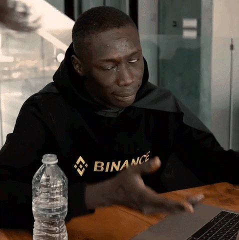 Man In Binance Hoodie Sitting At Table GIF