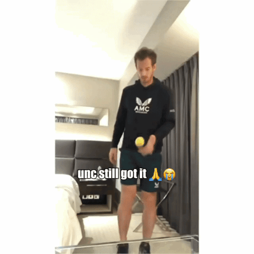 Man in Black AMC Sweatshirt Holding Tennis Ball