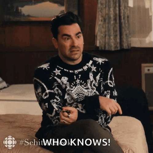 Man in Black and White Sweater Sitting on Bed Saying Schitwhoknows