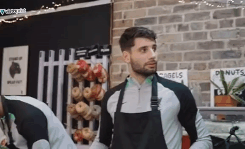 Man In Black Apron Standing In Front Of Brick Wall GIF