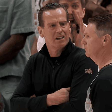 Man in Black Cavs Shirt Talking to Another Man