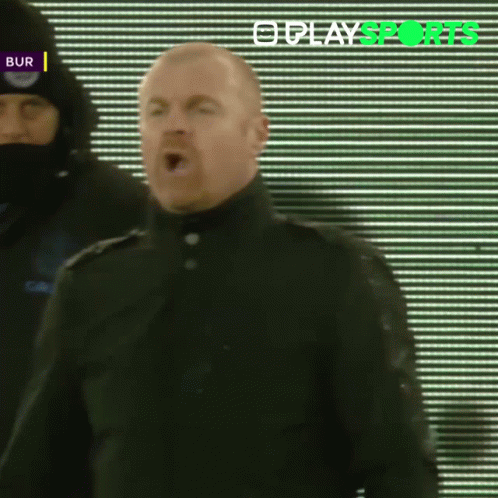 Man in Black Coat Standing in Front of Play Sports Screen
