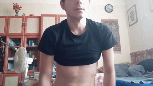 Man In Black Crop Top Standing In Room With Clock GIF