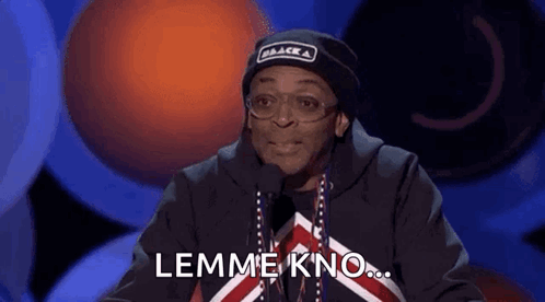 Man in Black Hat and Glasses Talking Into Microphone Saying Lemme Kno