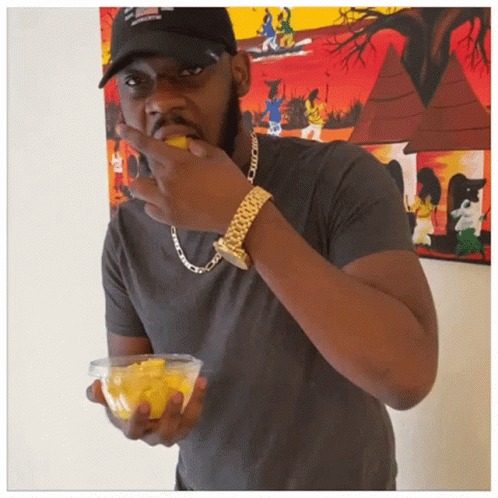 Man in Black Hat and Gold Watch Eating Fruit