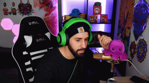 Man in Black Hat and Green Headphones Holding Octopus With Microphone