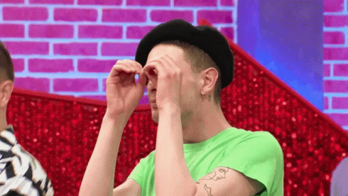 Man In Black Hat And Green Shirt Covering Eyes GIF