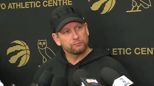 Man in Black Hat and Hoodie at Athletic Center Sign