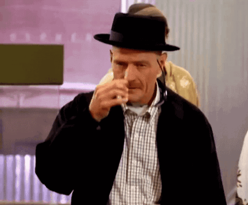 Man in Black Hat and Plaid Shirt Holding Nose