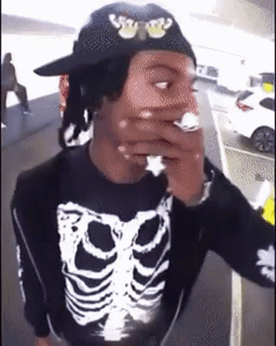 Man in Black Hat and Skeleton Shirt Smoking Cigarette