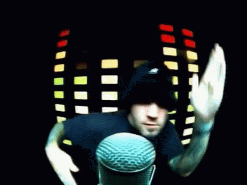 Man in Black Hat Waving at Microphone