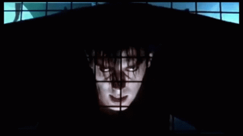 Man in Black Hood Standing in Front of Window
