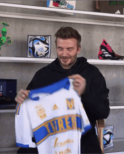 Man in Black Hoodie Holding White and Blue Tigres Jersey