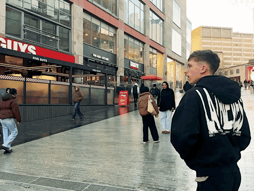 Man in Black Hoodie in Front of Five Guys