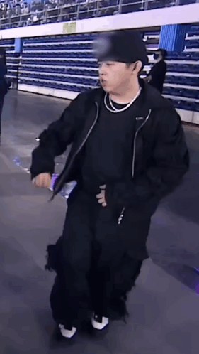 Man In Black Jacket And Hat Holding Water Bottle In Stadium GIF
