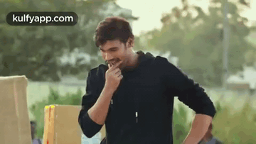 Man In Black Jacket Eating In Front Of Box GIF
