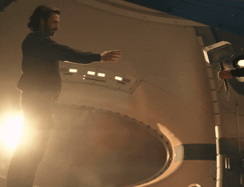 Man In Black Jacket Holding Hammer In Dark Room GIF