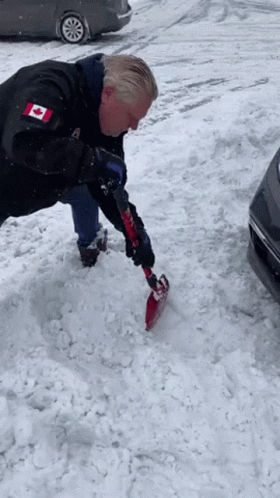 Man in Black Jacket with Canadian Flag Shoveling Snow
