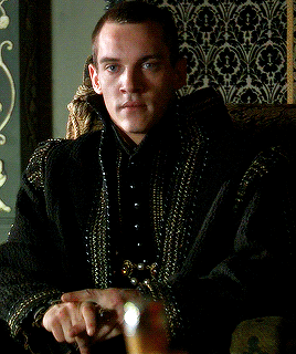 Man in Black Jacket With Gold Beads Sitting in Chair