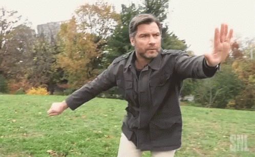 Man in Black Jacket with SNL Logo in Grassy Field