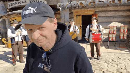 Man In Black Puma Hat With Musicians GIF