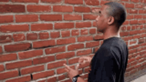 Man in Black Shirt at Brick Wall