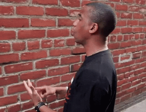 Man In Black Shirt By Brick Wall GIF