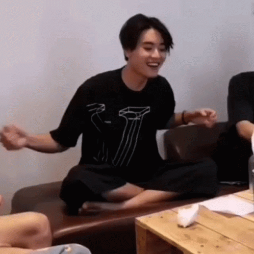 Man In Black Shirt Cross-Legged Laughing On Couch GIF