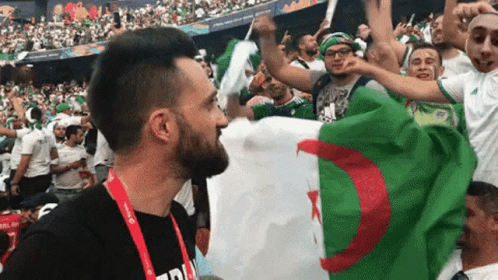 Man in Black Shirt Holding Flag Before Crowd