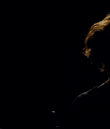 Man in Black Shirt in Front of Circle in Dark