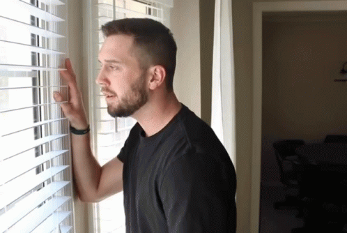 Man in Black Shirt Looking Out Window