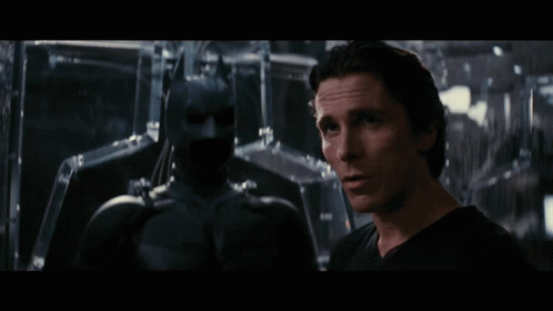 Man in Black Shirt Next to Batman Statue