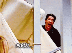 Man In Black Shirt Peeking Behind Couch Saying Pivot GIF